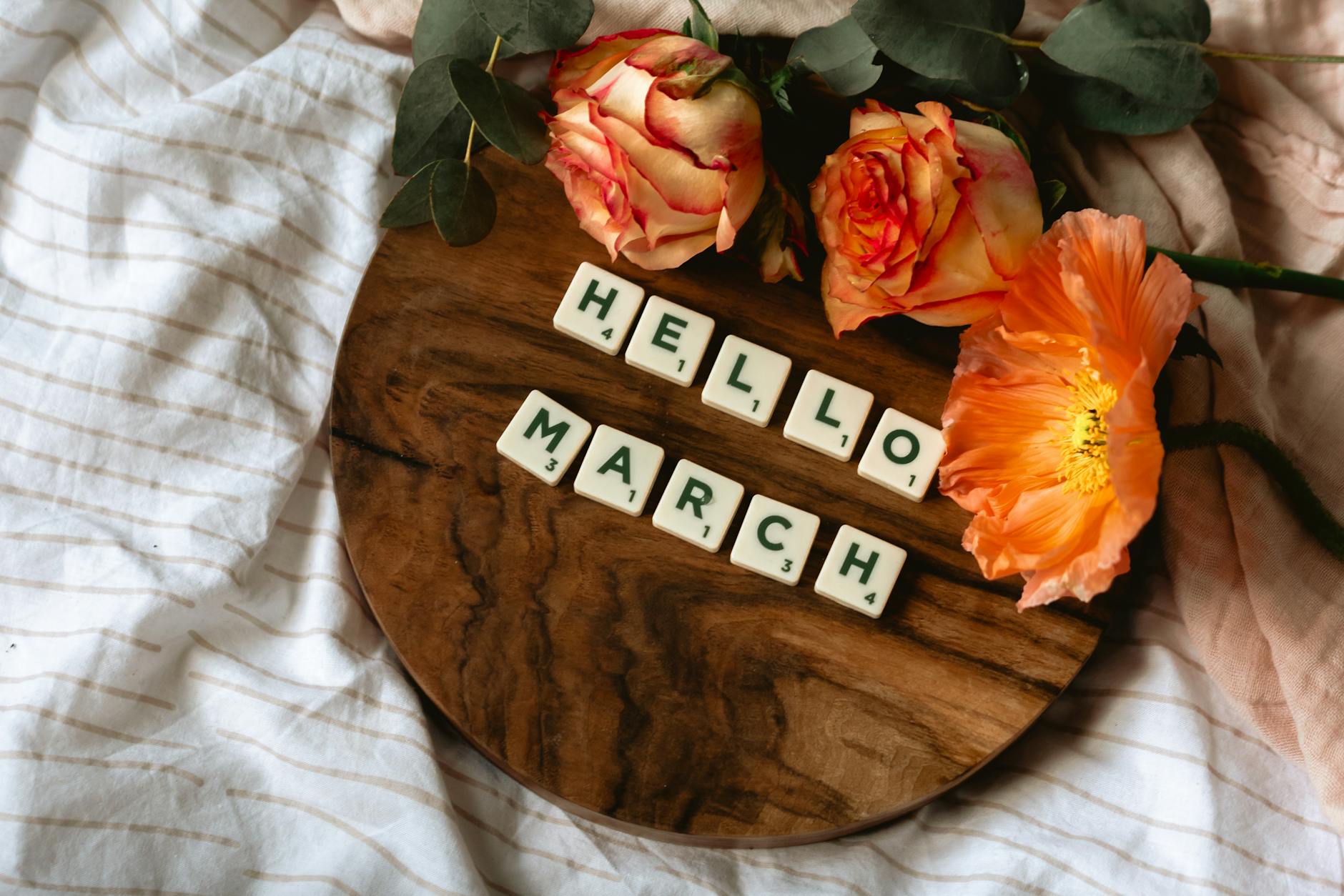 top view of scrabble tiles on wooden surface near flowers